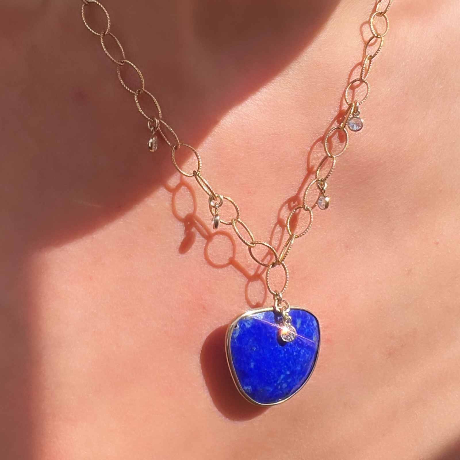 Lapis gemstone necklace on a textured oval gold filled chain with cx charms on a models neck | Camille Jewelry 